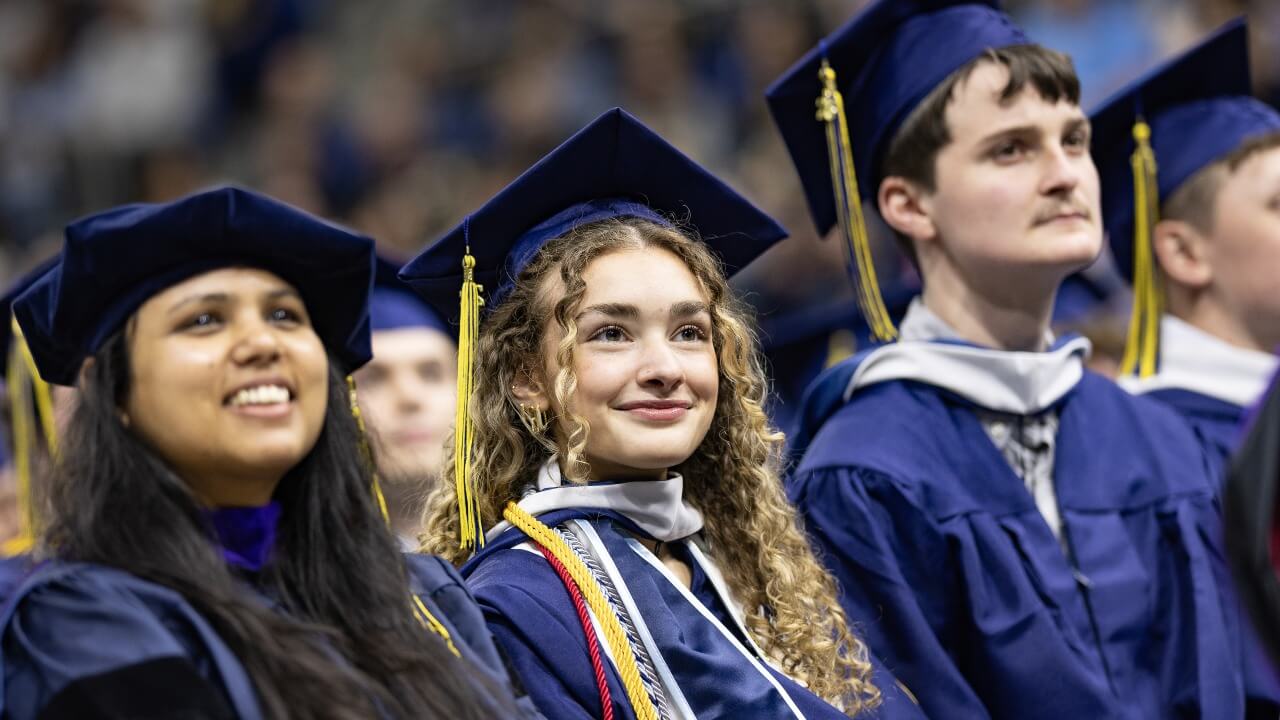 Graduate smiling sitting in the row of graduates