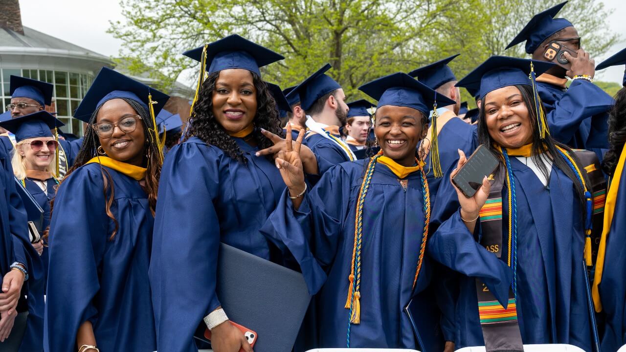 Graduates posing and holding up peace signs with their diplomas