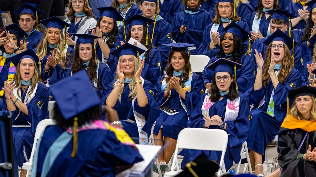 Graduates clapping and cheering as they look at the School of Education student speaker