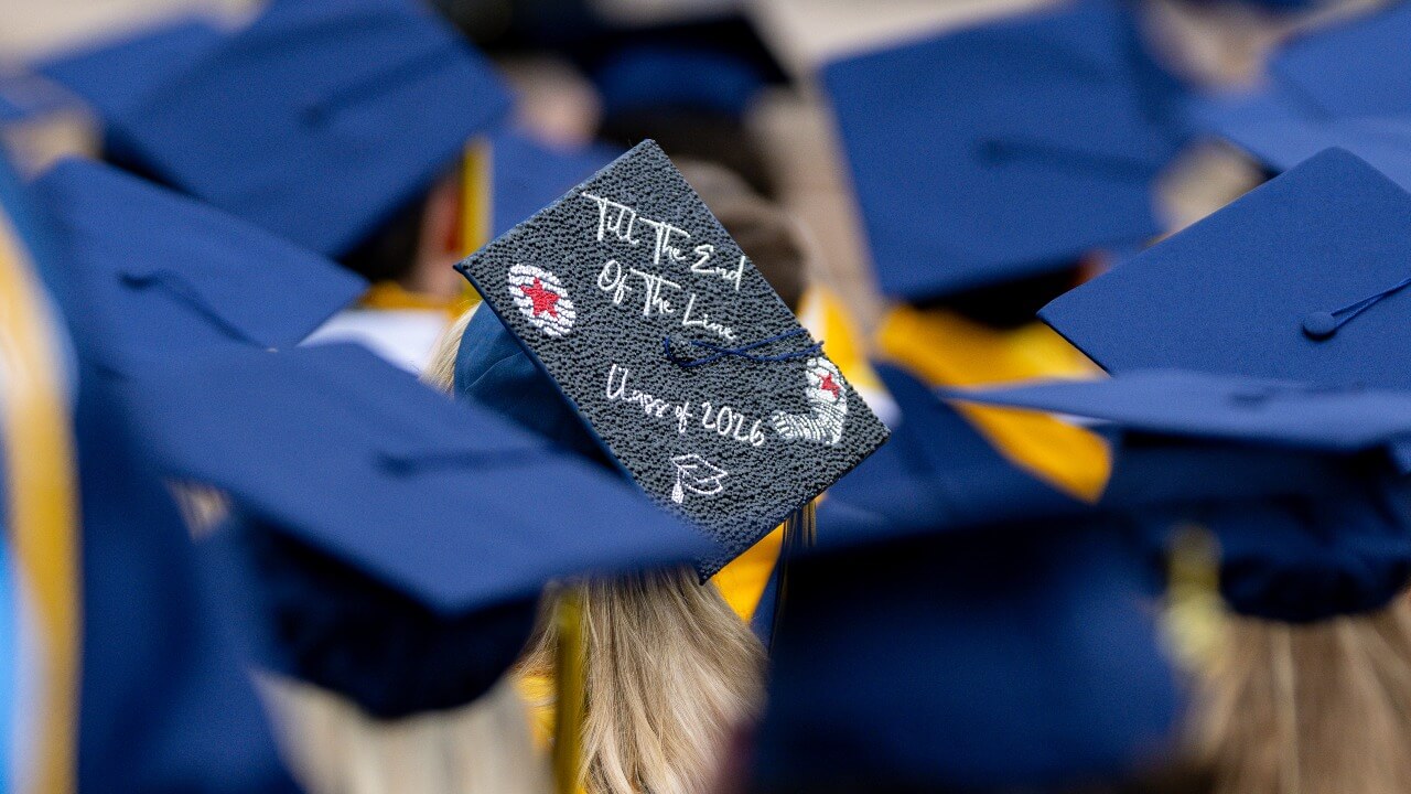 Zoomed in view of a graduate cap that says "Til the end of the line, Class of 2026"