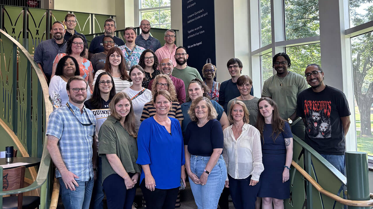 Faculty poses for a picture standing on stairs.
