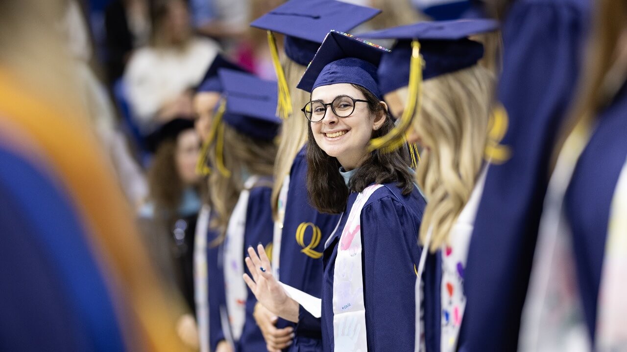 graduate smiling and waving to camera