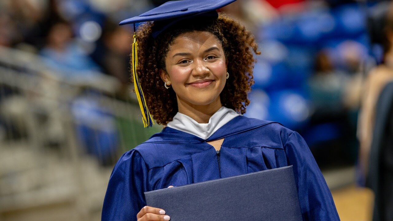 Graduate smiles and holds up diploma