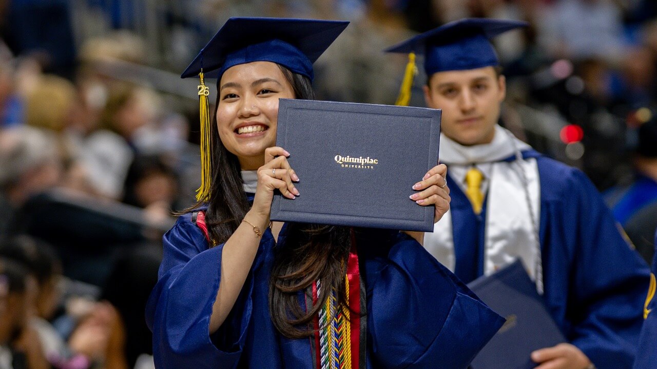 Graduate smiles and holds up diploma