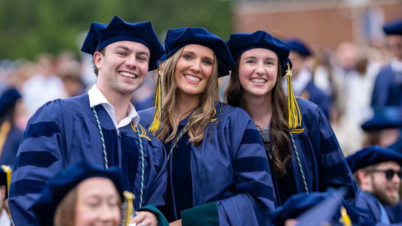 Three graduates posing together and smiling
