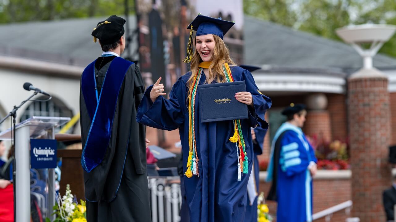 Graduate walking off the stage and making a fun face to the camera