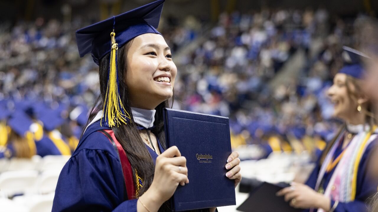 Graduate holding up their diploma and smiling
