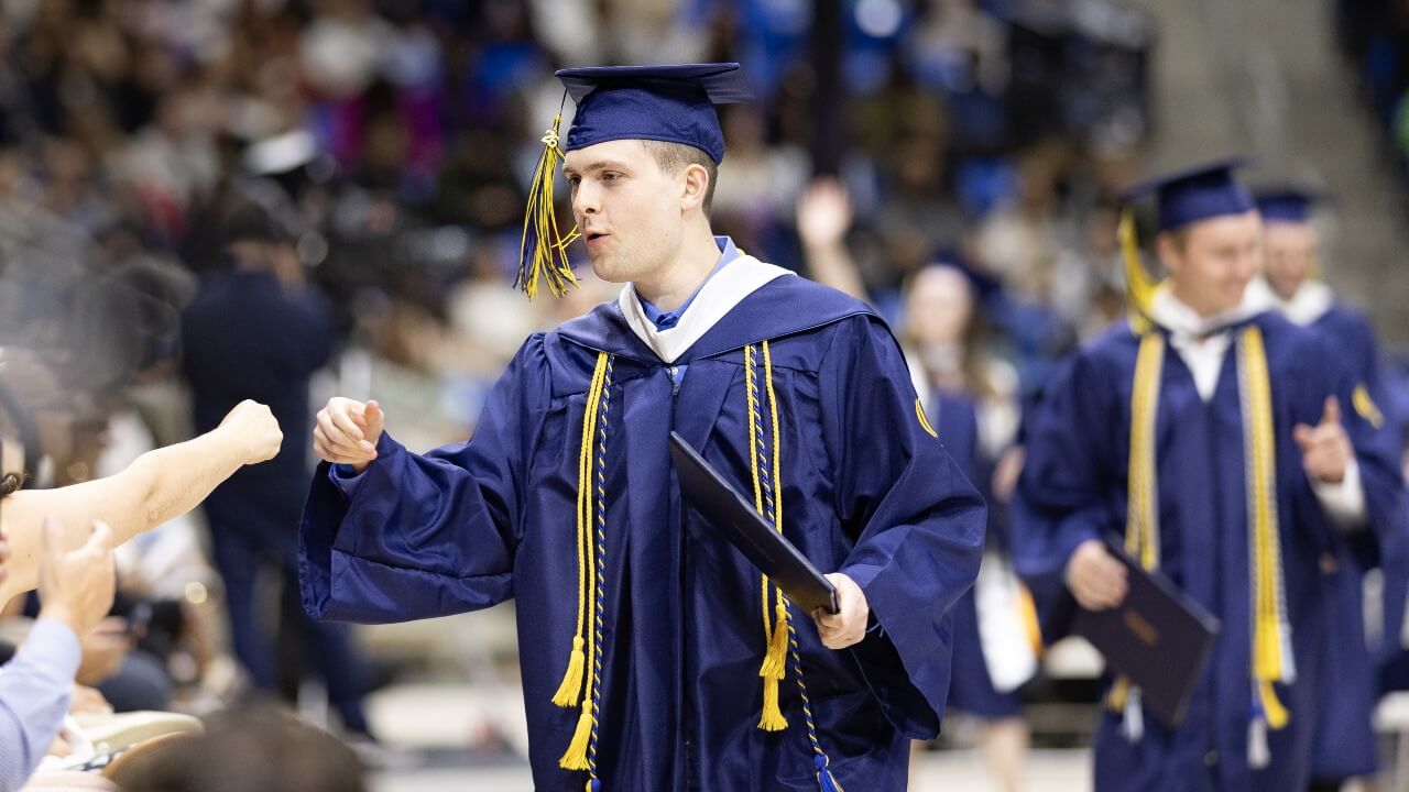 Graduate giving another person a fist bump