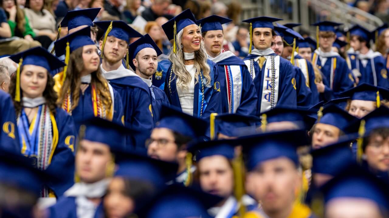 Graduates in caps and gowns stand in a line.