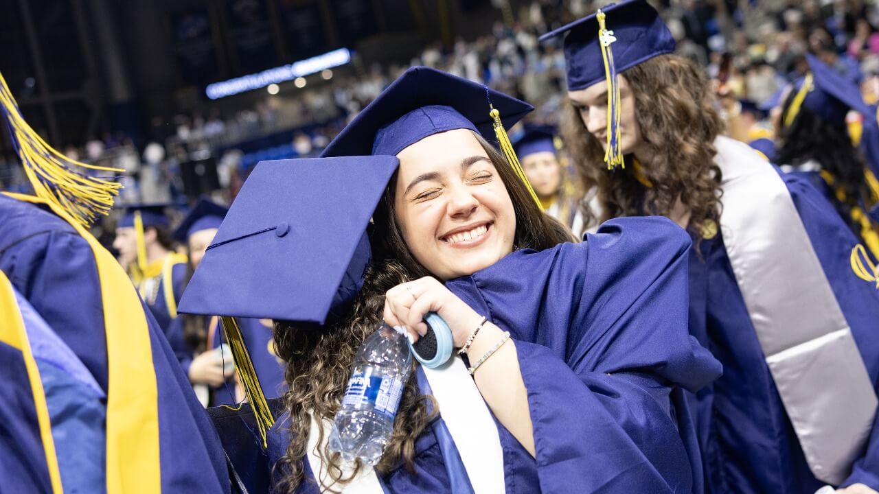 Two graduates hugging in the crowd