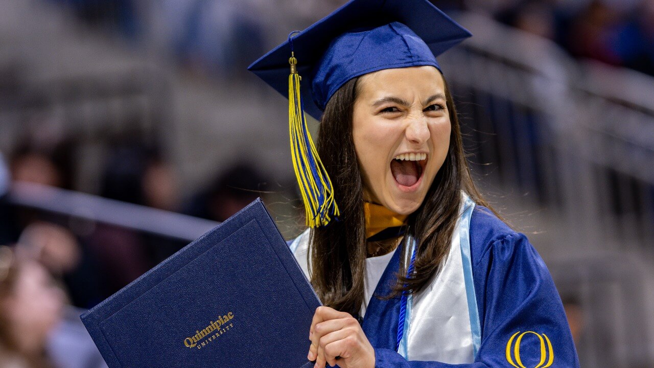 Graduate smiles with their degree.