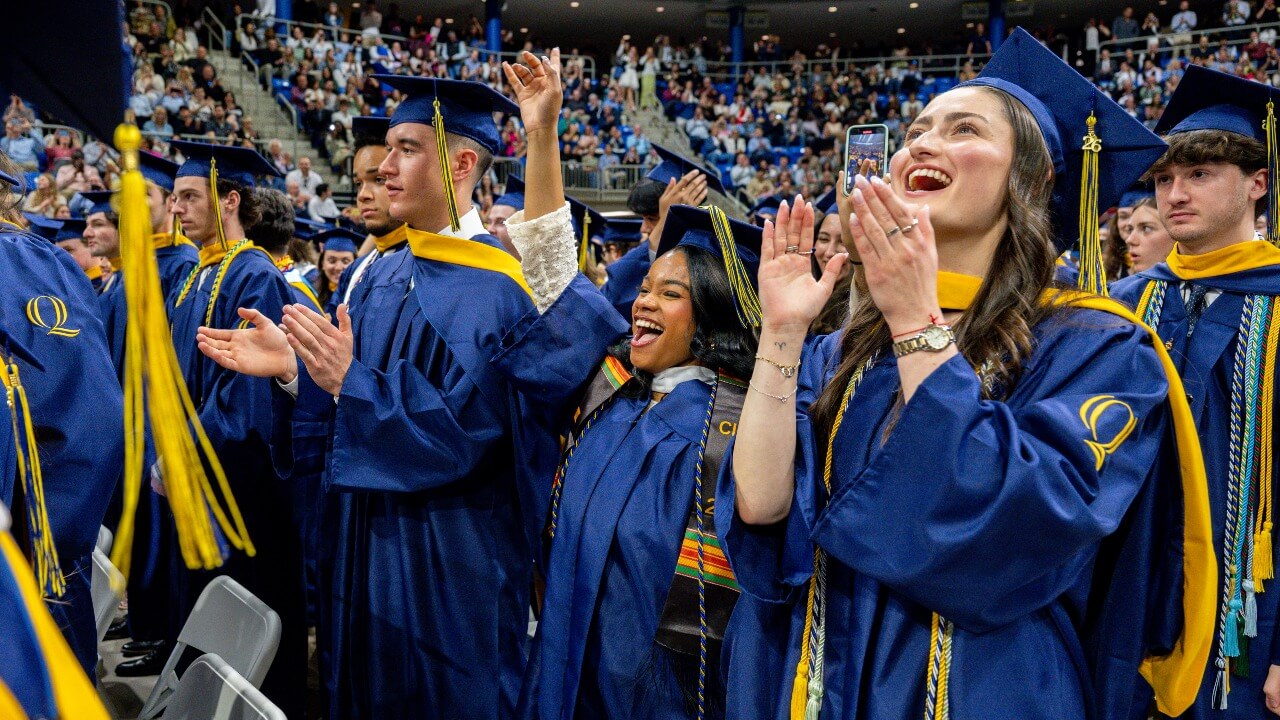 Graduates in caps and gowns cheer.