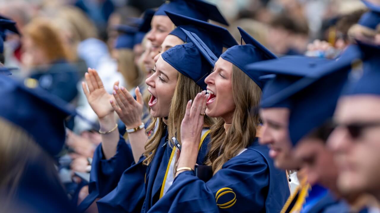 two graduates hollering with joy from the crowd