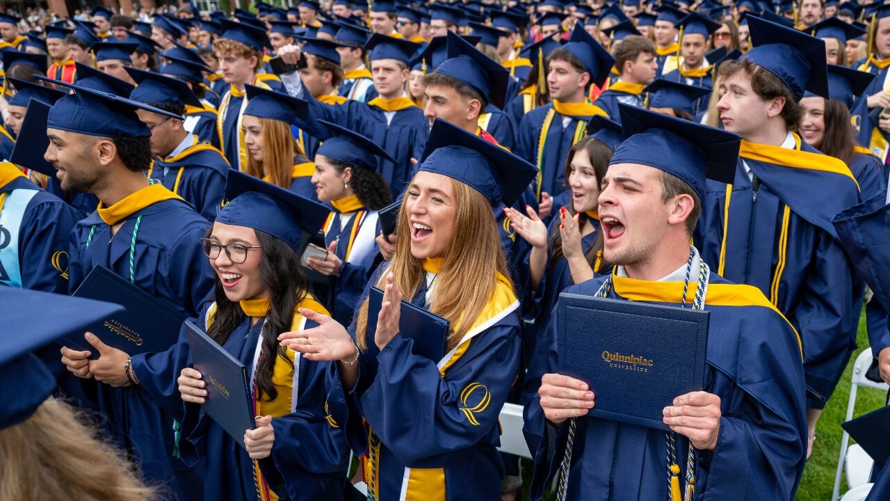 Crowd of graduates cheering and clapping for their peers