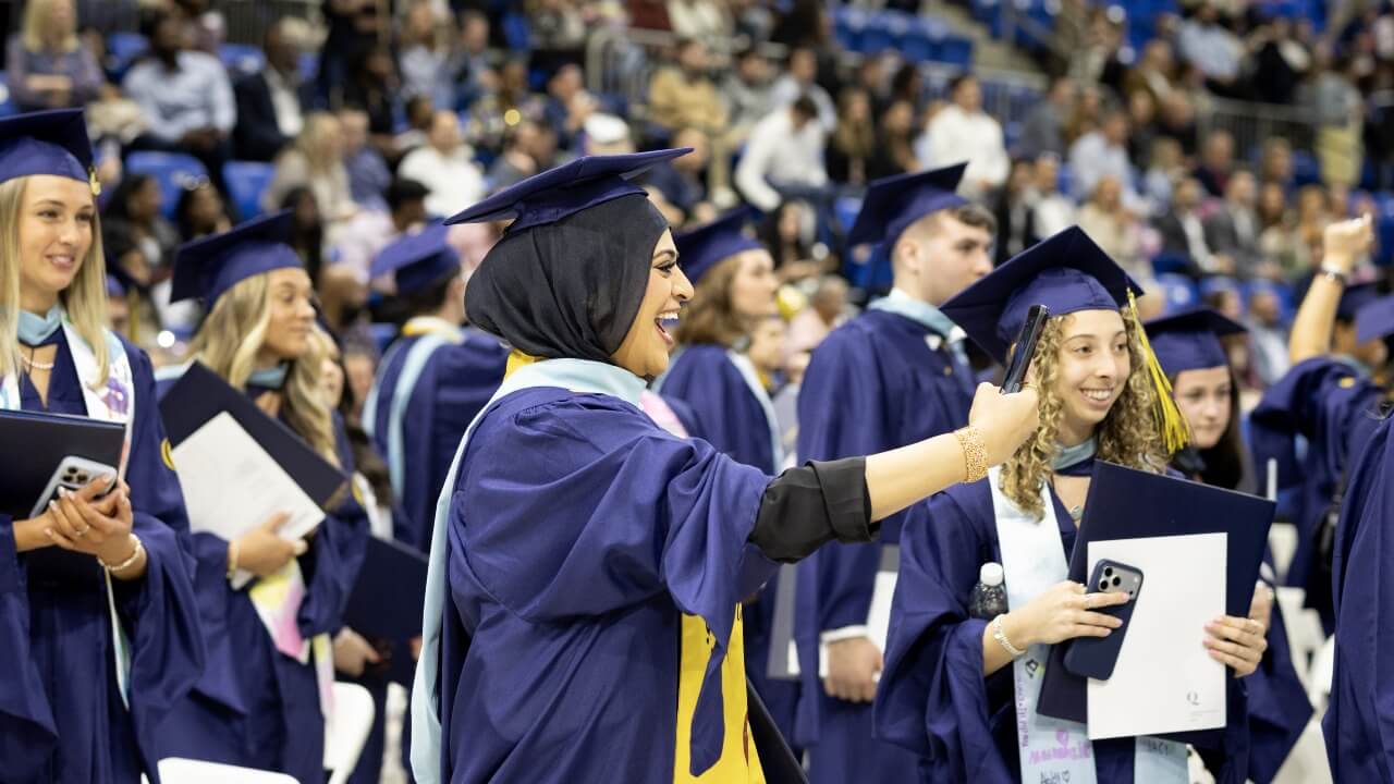 Graduate taking a selfie with their phone in their regalia