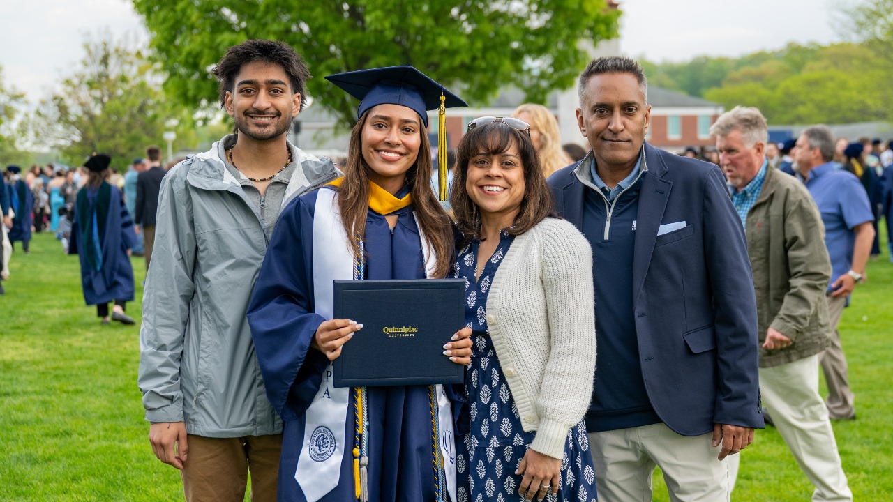 graduate In cap and gown posing for a family photo with their loved ones