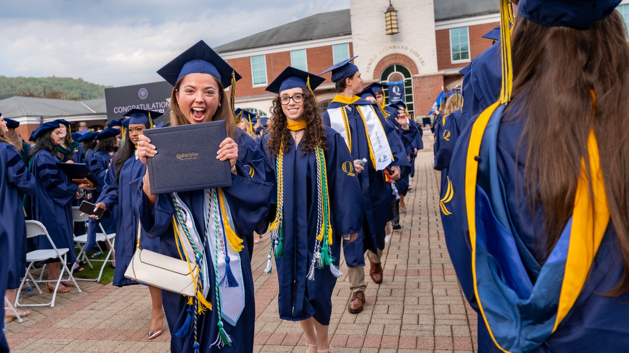 hundreds of graduates excited in the ceremony- one holding their diploma and hollering with joy