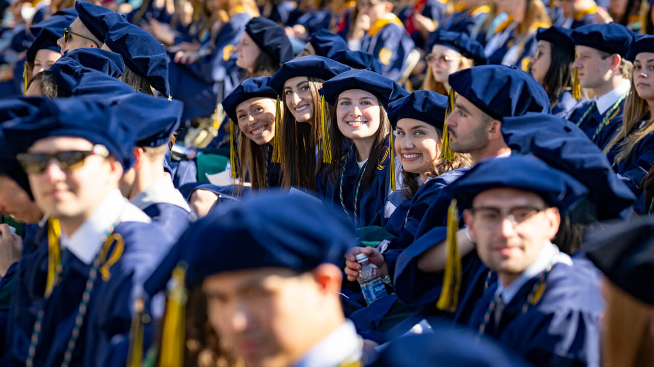 Four grads next to each other smile together
