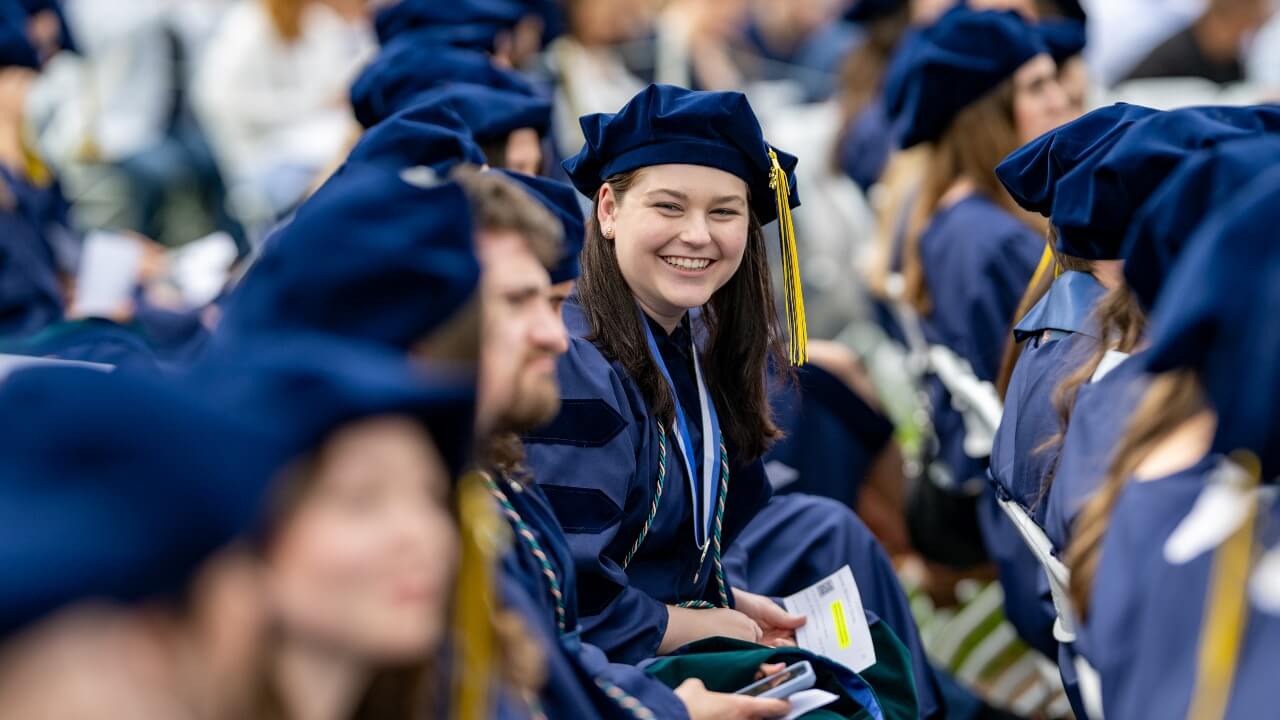 Graduate in doctoral regalia smiling down the row