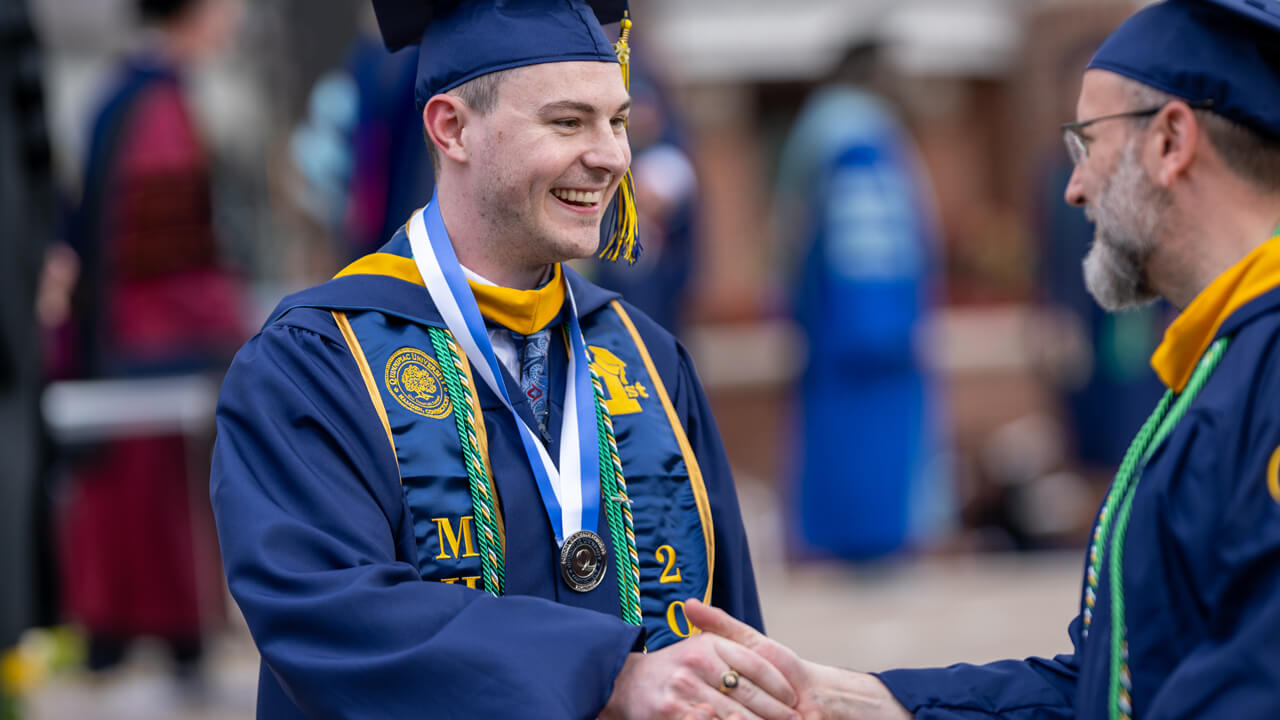 Graduates smile and shake hands