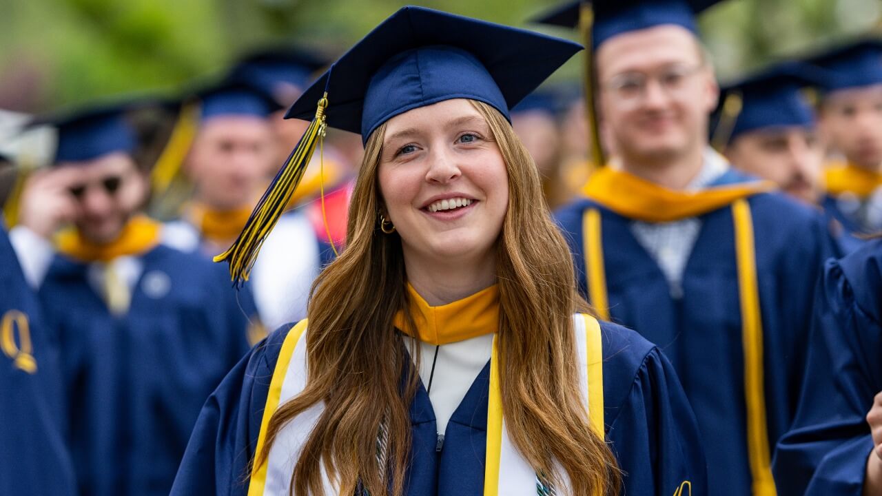 Graduate smiling at the camera in their regalia