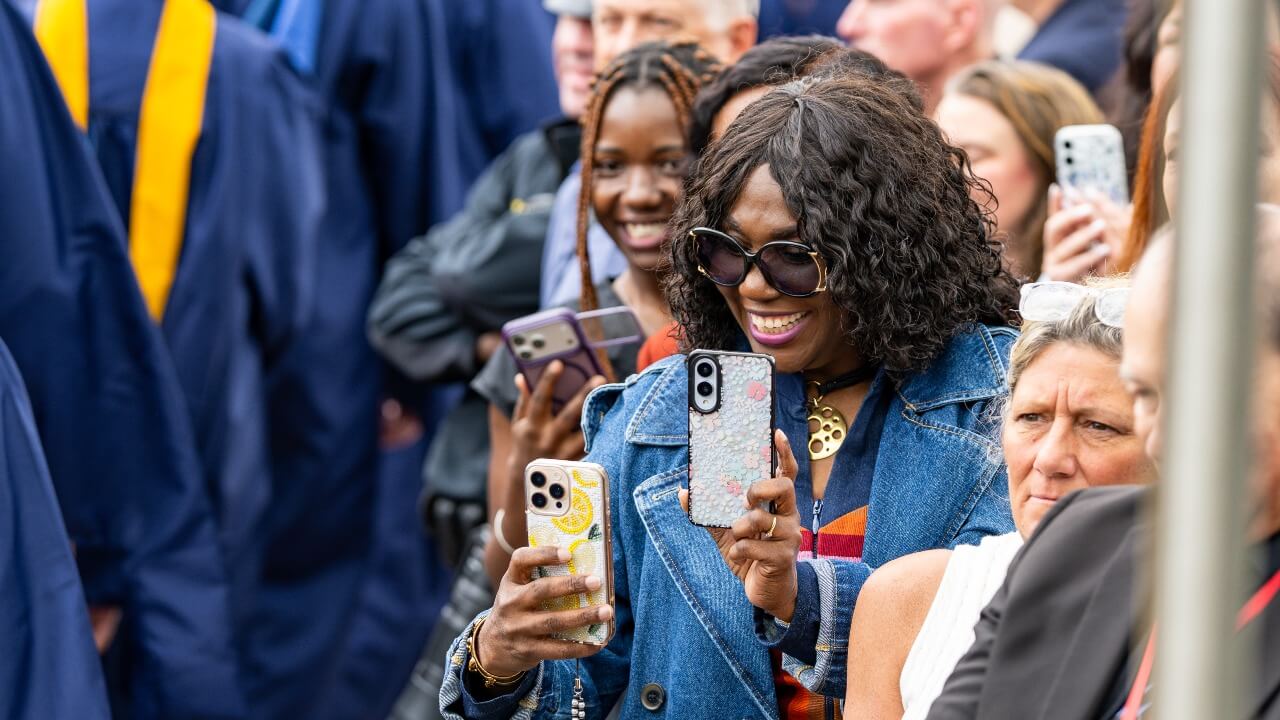 Loved one of graduate happily takes a photo during graduation ceremony