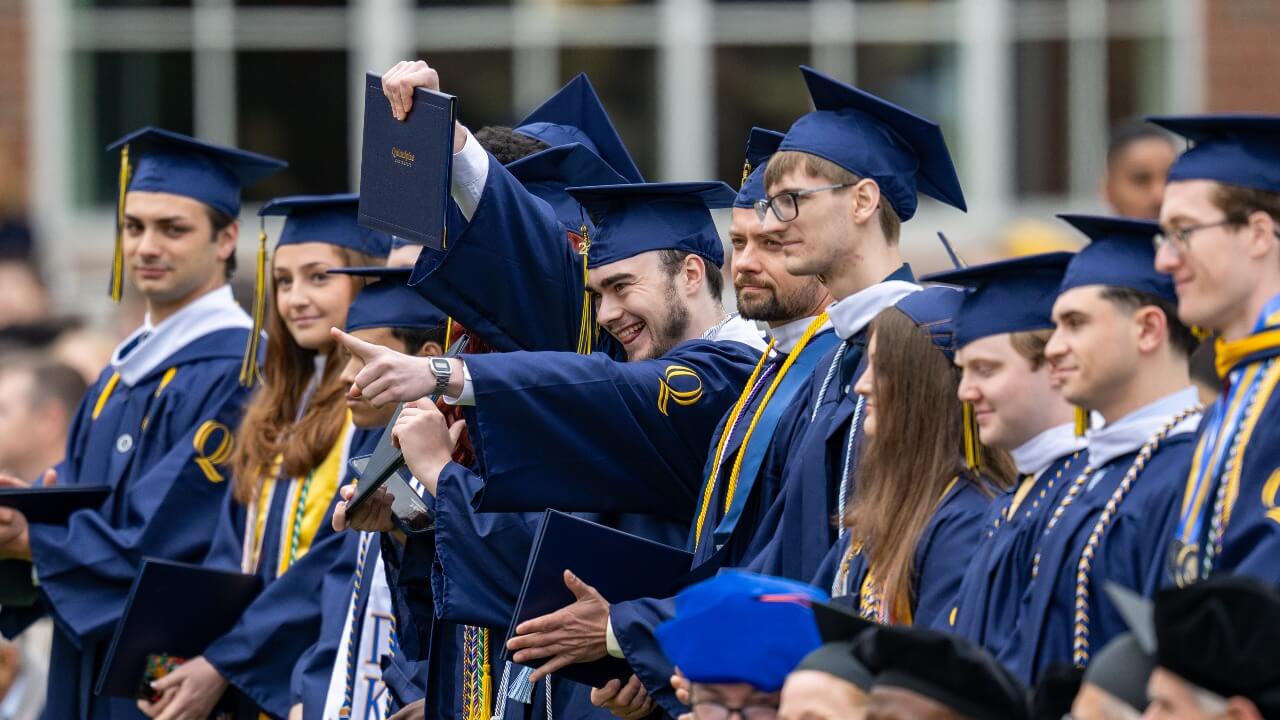 A row of graduates sitting and cheering