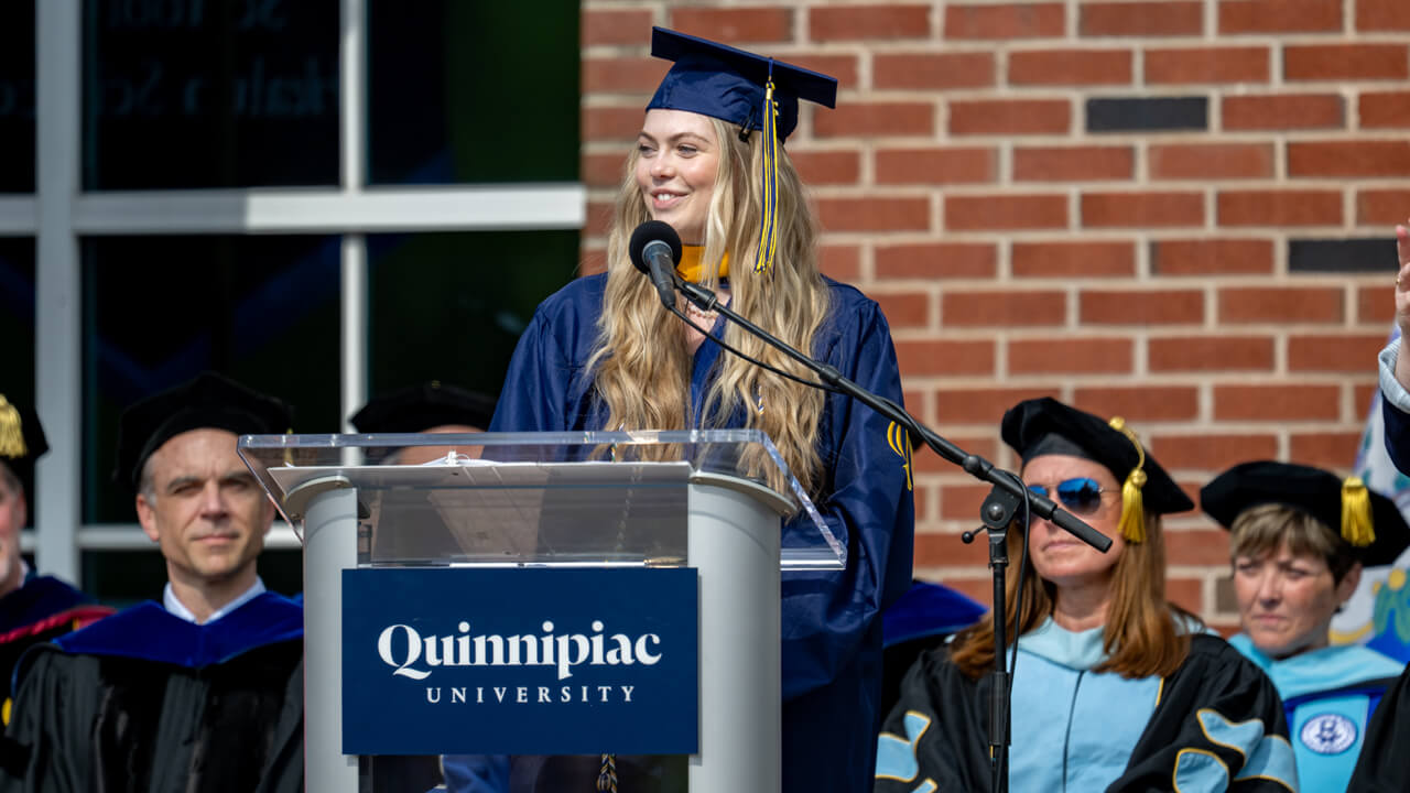 Abigail Lambert smiles as she speaks at the Commencement podium
