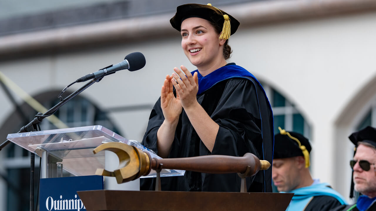 Sophia Marshall claps behind the microphone on the library steps