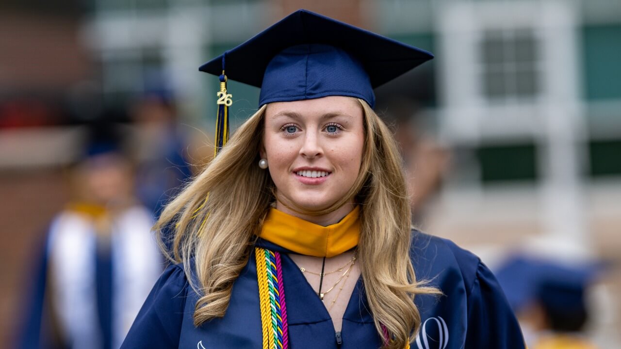 Graduate looking at the camera and smiling in their regalia
