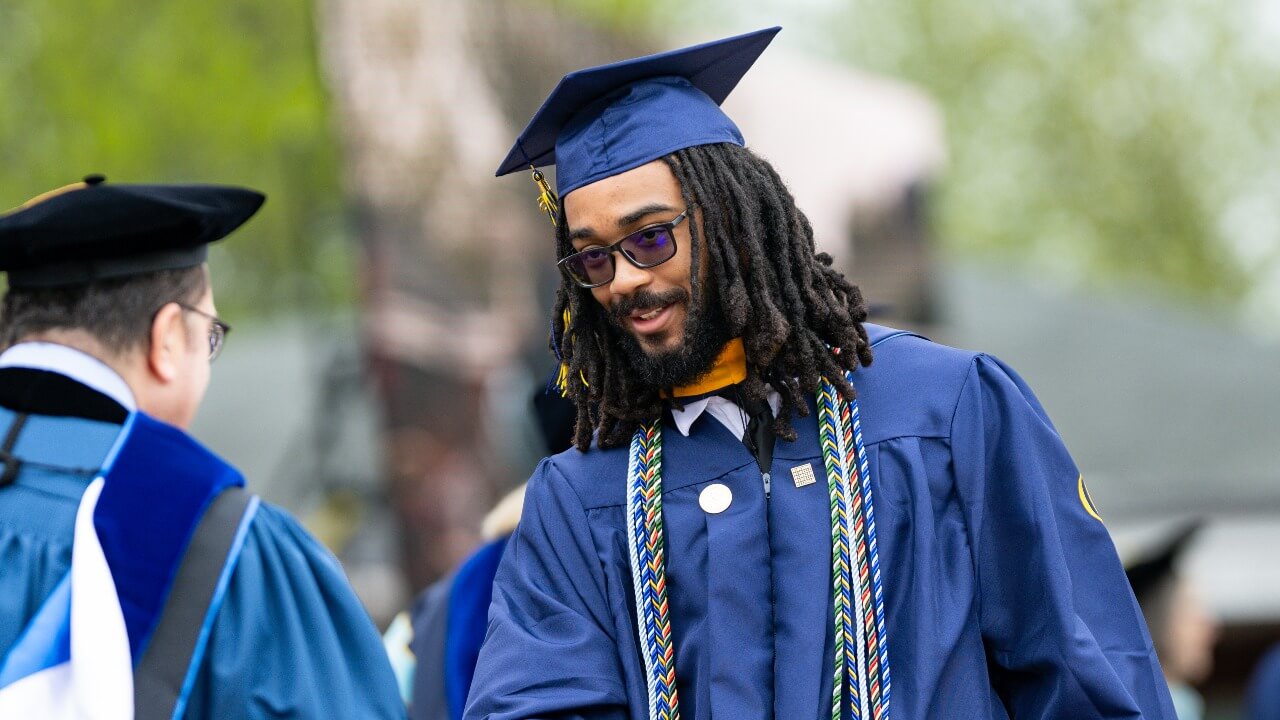 Graduate facing to the left and shaking hands with the dean