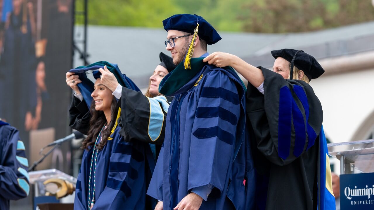 two graduates standing side by side receiving their hoods