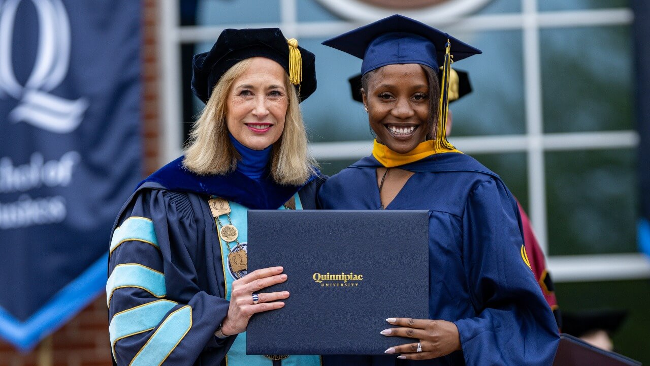 Graduate holds diploma next to President Hardin