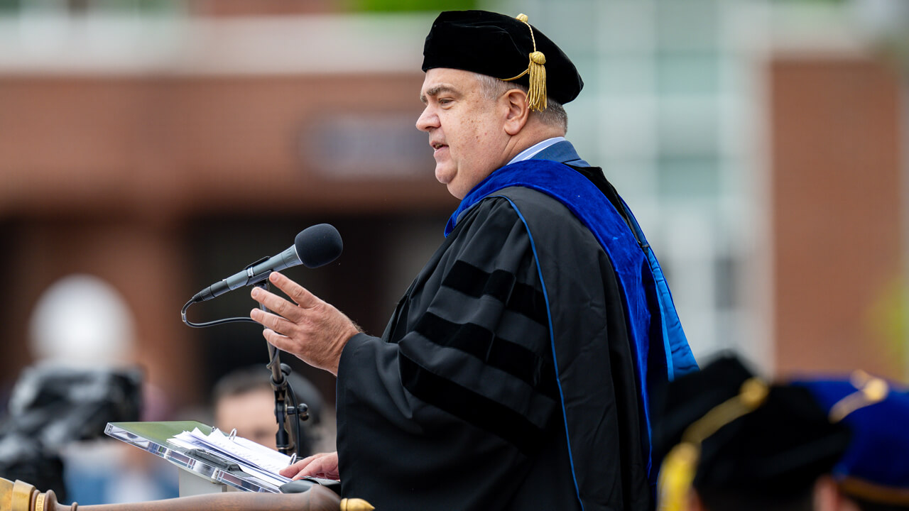 Side view of Robin Hayes addressing the graduates from a podium