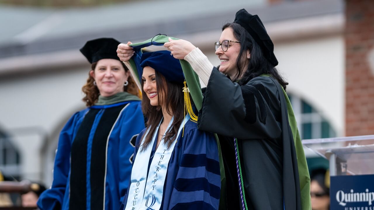 Faculty member hooding a graduate on the library steps