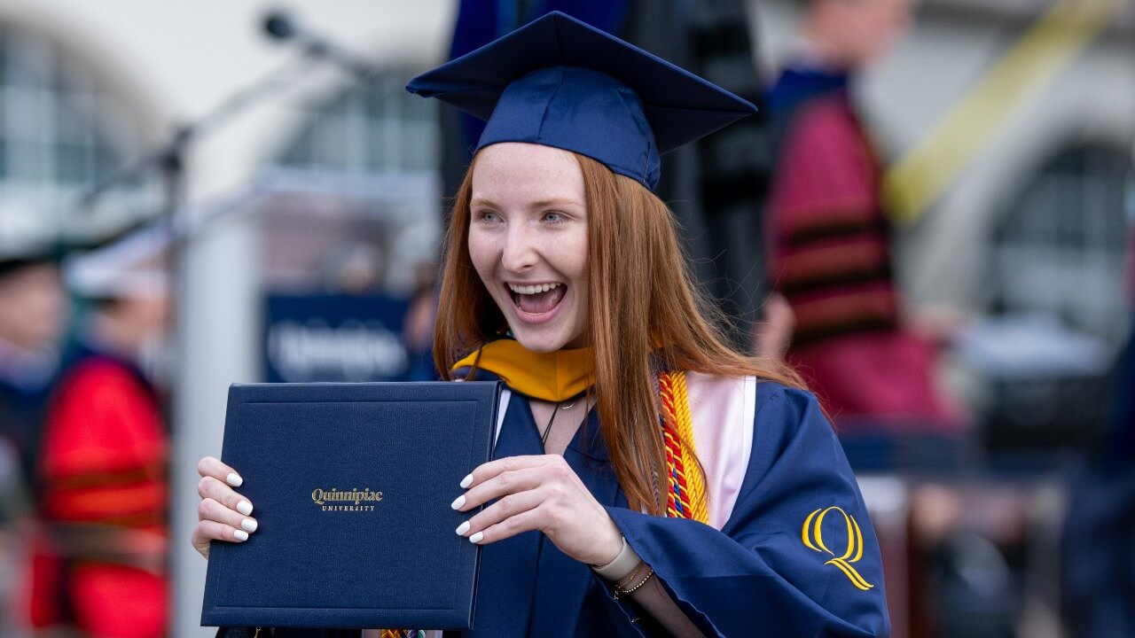 Graduate in cap and gown smiles with degree