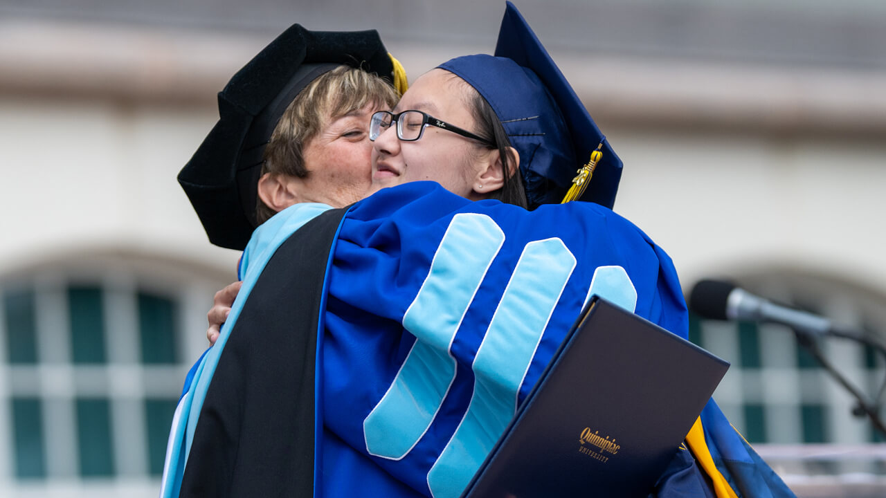 Monique Drucker embraces her daughter as she holds her diploma