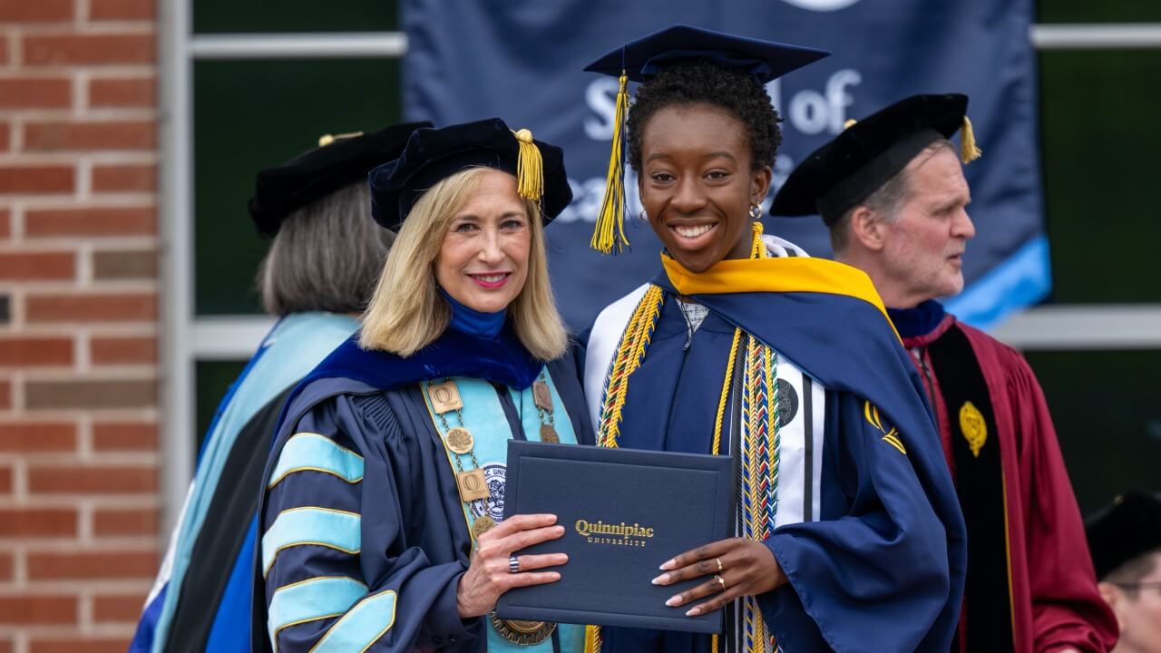 Marie and a graduate holding up a diploma together