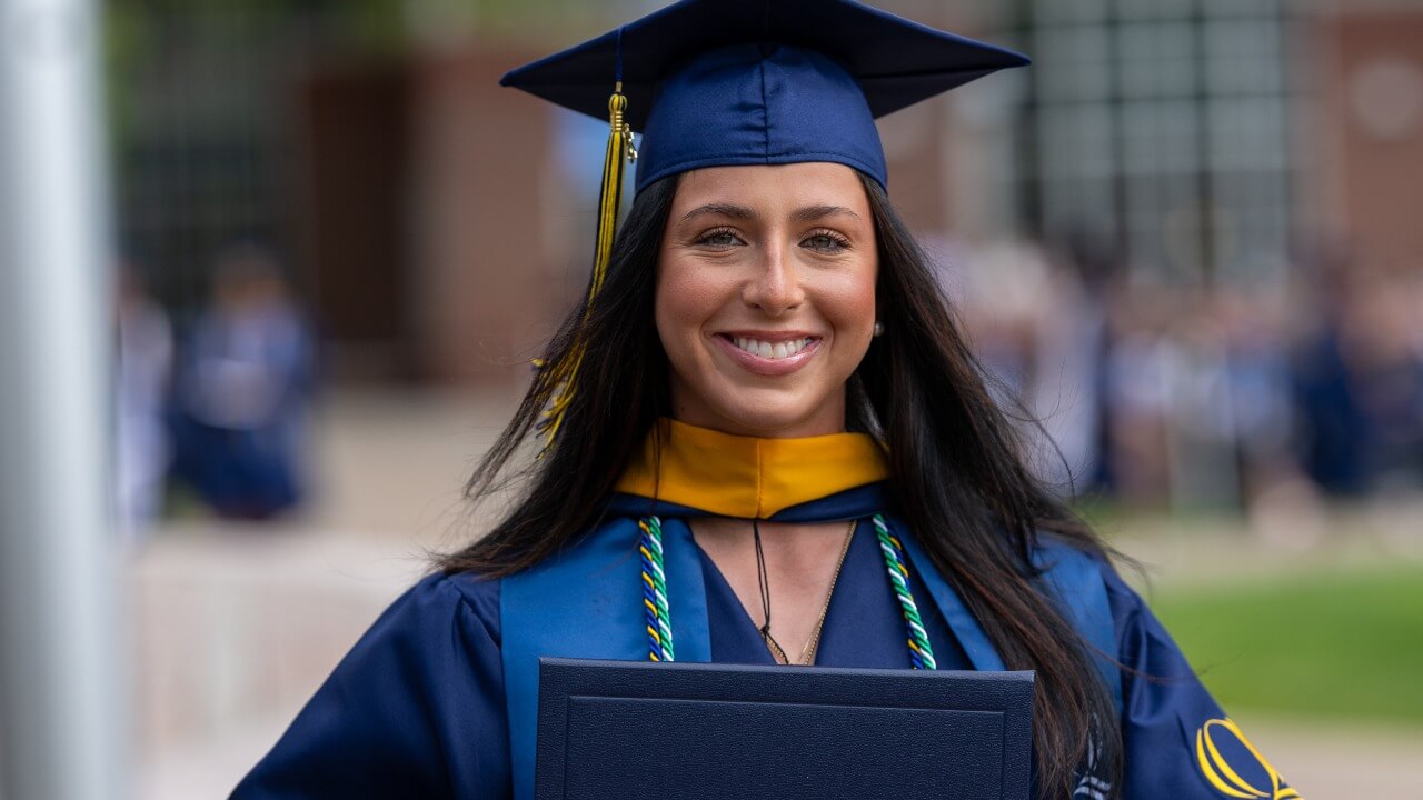 a graduate in their cap and gown smiling at the camera