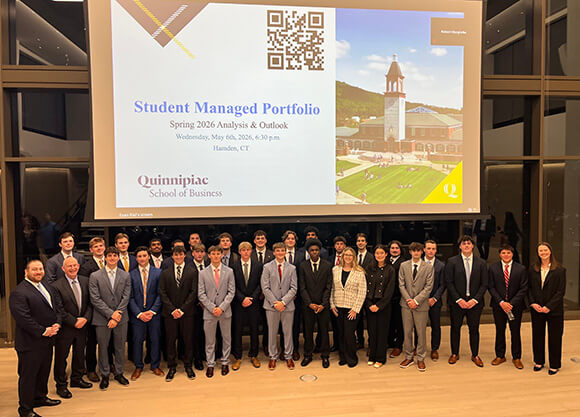 Group of students standing in front of the student managed portfolio presentation
