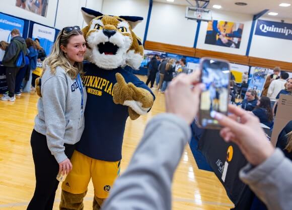 Student smiling and taking a photo with Boomer