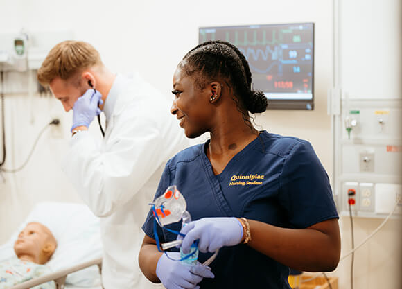 Nursing student looking towards peer who is practicing clinical skills