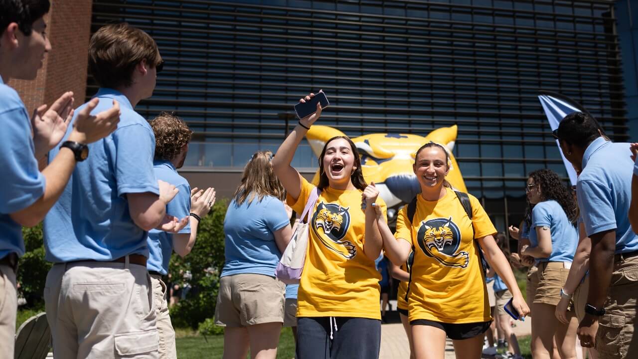 Students holding hands and cheering as they walk out of Orientation