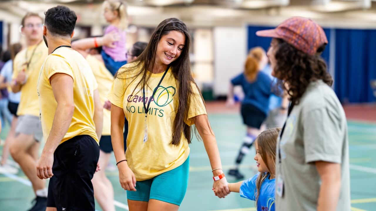 Camper and volunteer holding hands together