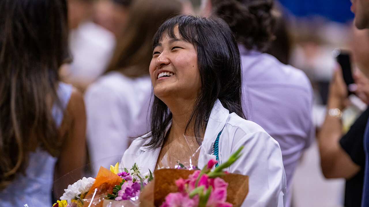 Student holding flowers and smiling