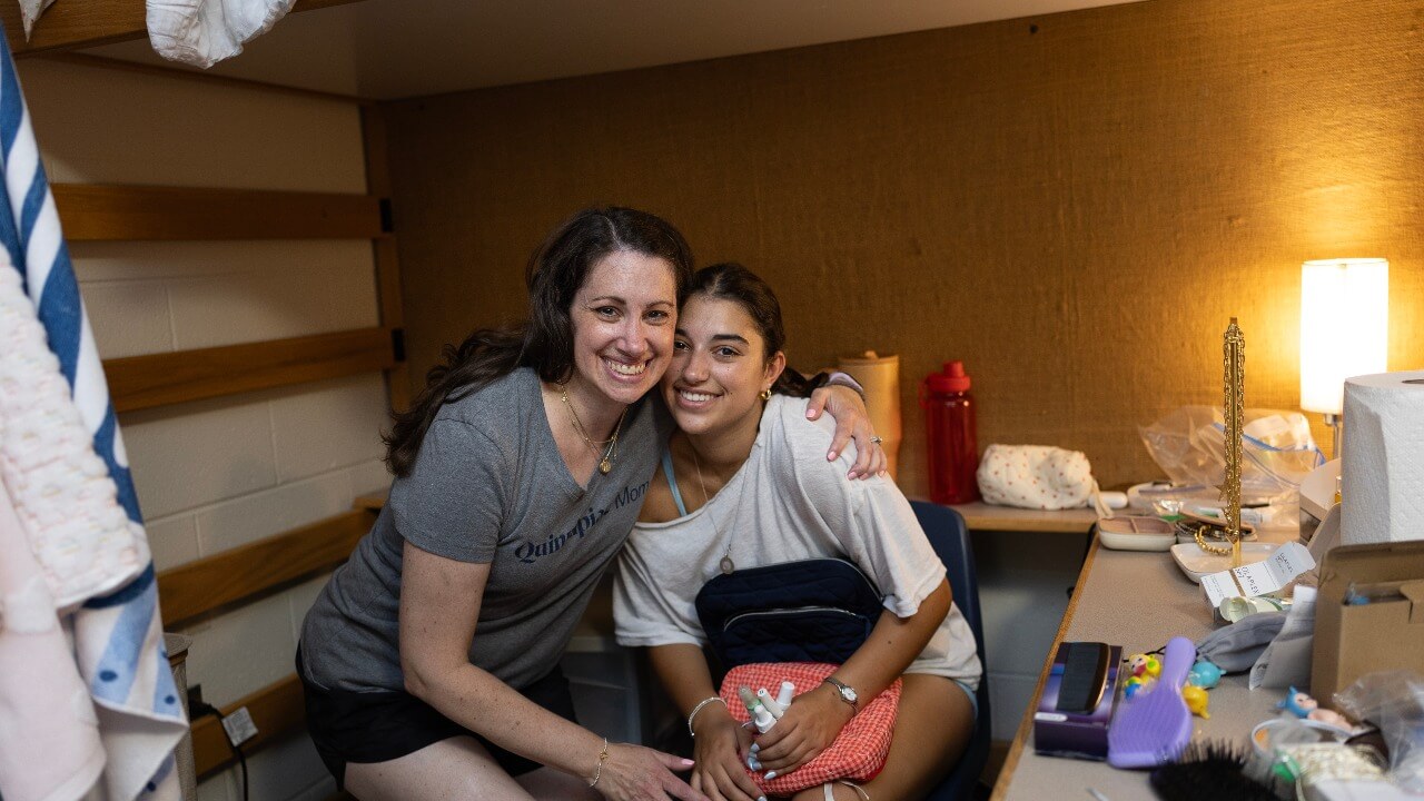 Parent and new student smile in residence hall room