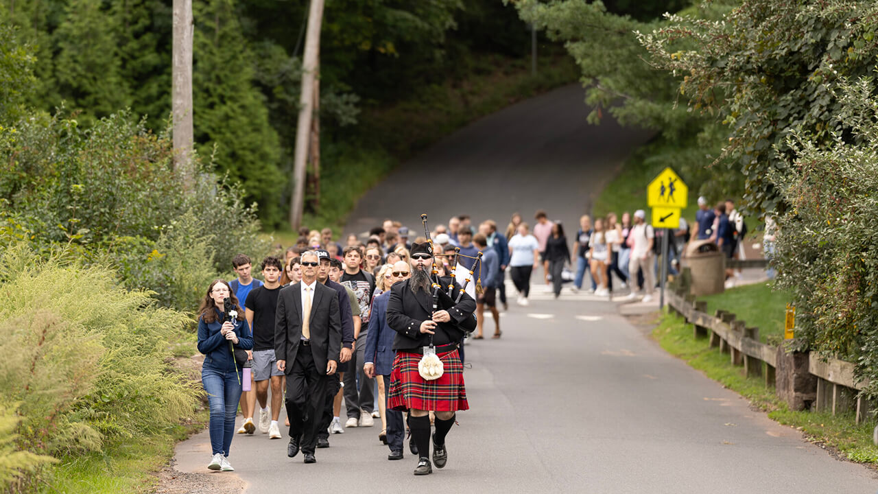 Bagpiper leading procession down Hogan Road